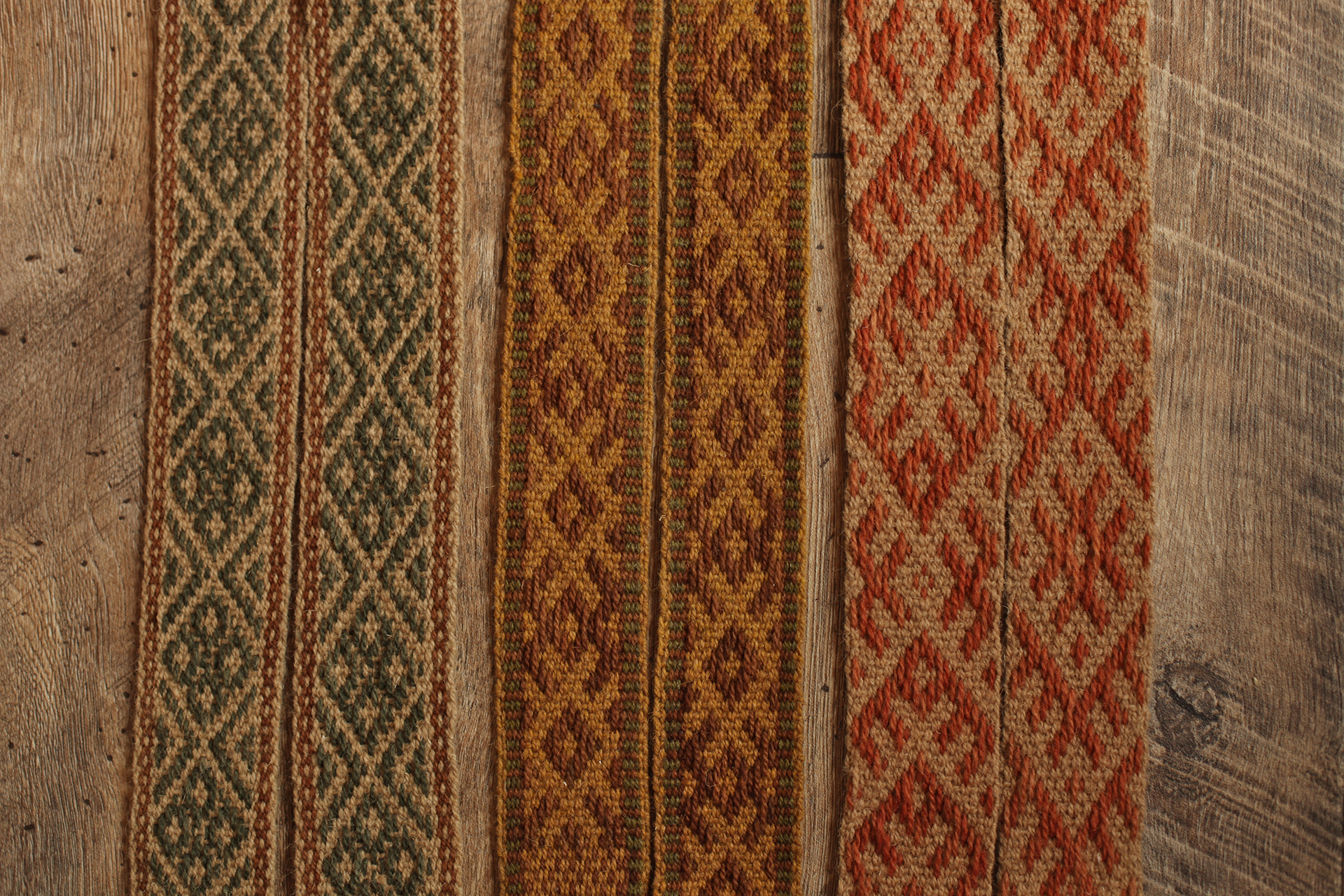 Zdjęcie przedstawia trzy tkane pasy, zwane krajkami ułożone równolegle przy sobie. Praca została wykonana z prezentowanych powyżej włóczek. Kolorystyka wszystkich trzech krajek jest ciepła i stonowana. Praca inspirowana jest kulturą słowiańską