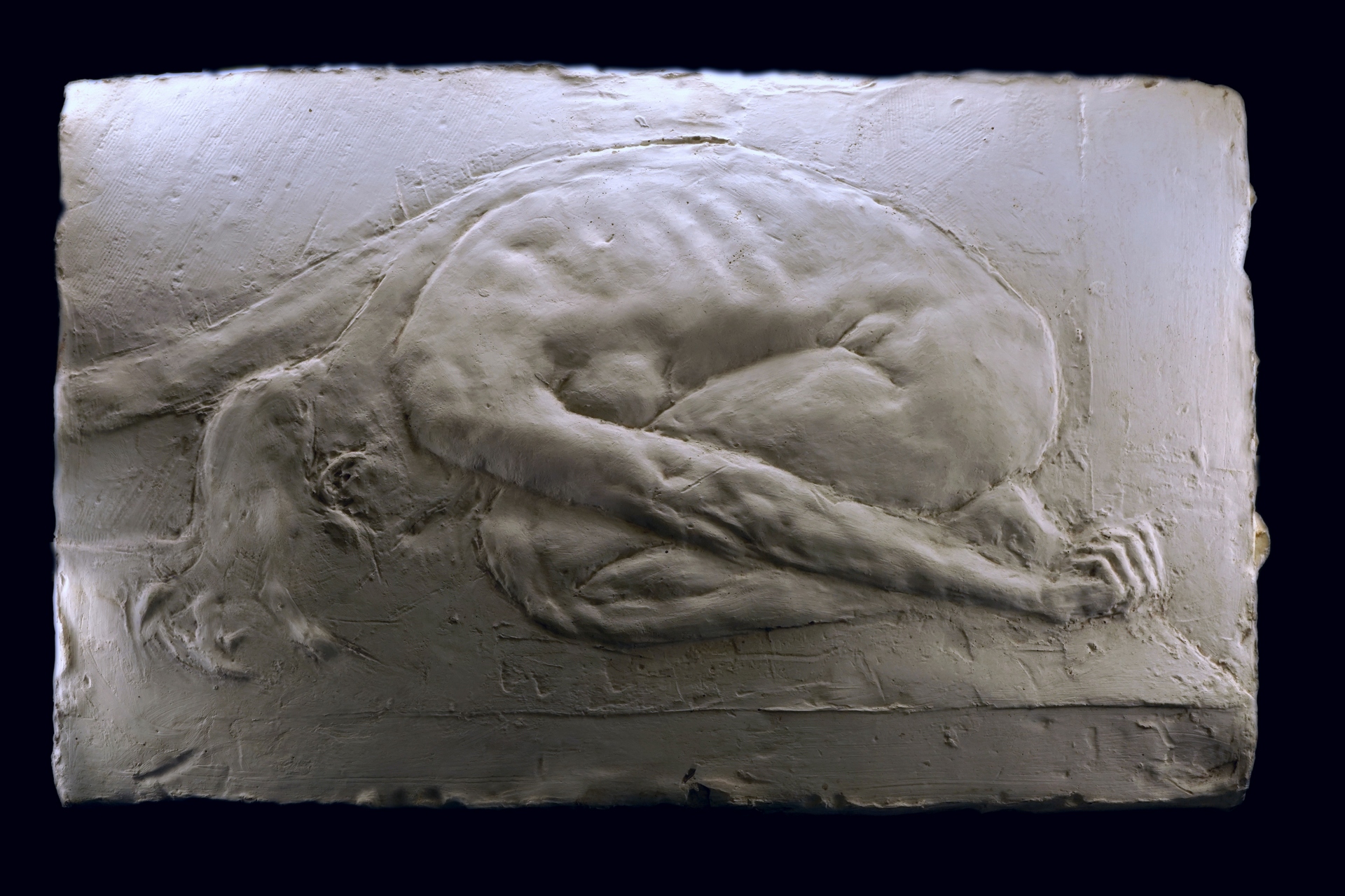 Anna Mandziak - zdjęcie przedstawia subtelną płaskorzeźbę aktu kobiecego ujętego w pozycji skulonej, jakby w ukłonie, wykonana w gipsie.
