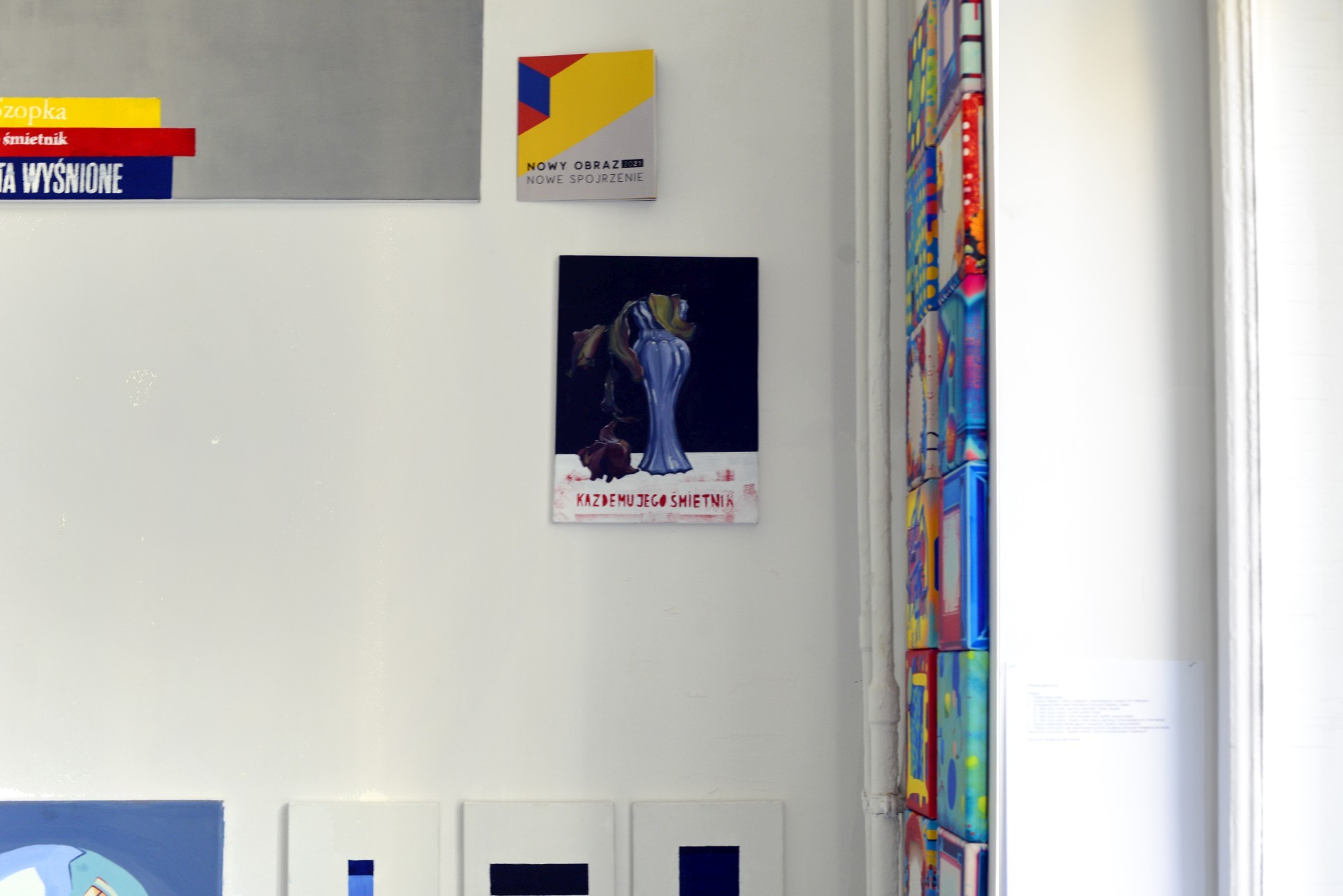 Zdjęcie przedstawia ścianę w pracowni. Z prawej strony obraz z uschniętym tulipanem w wazonie