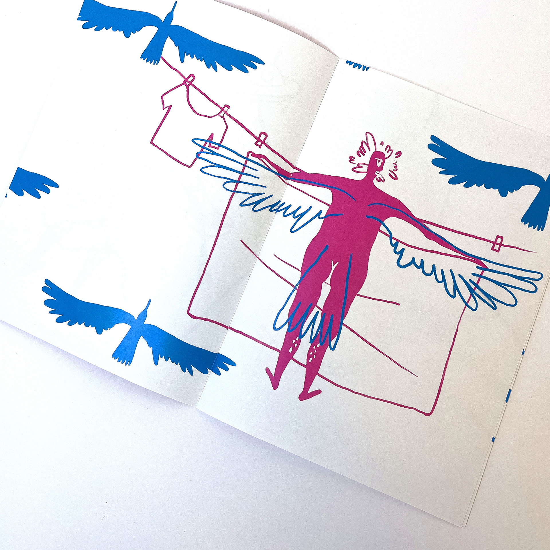 Fotografia przedstawia rozkładówkę folderu widoczna ilustracja w kolorach niebiesko różowym przedstawiająca kobietę wieszającą pranie z dorysowanymi skrzydłami.