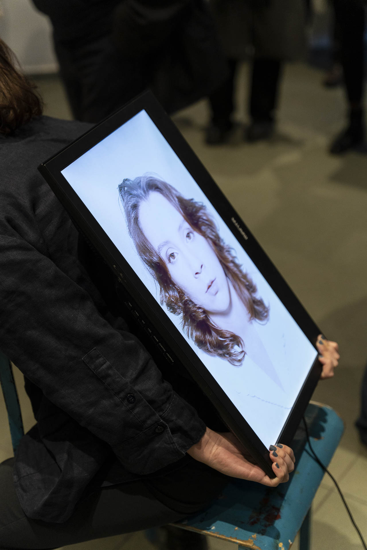 Zdjęcie portretowe młodej kobiety widoczne na ekranie monitora trzymanego w dłoniach w pozycji pionowe