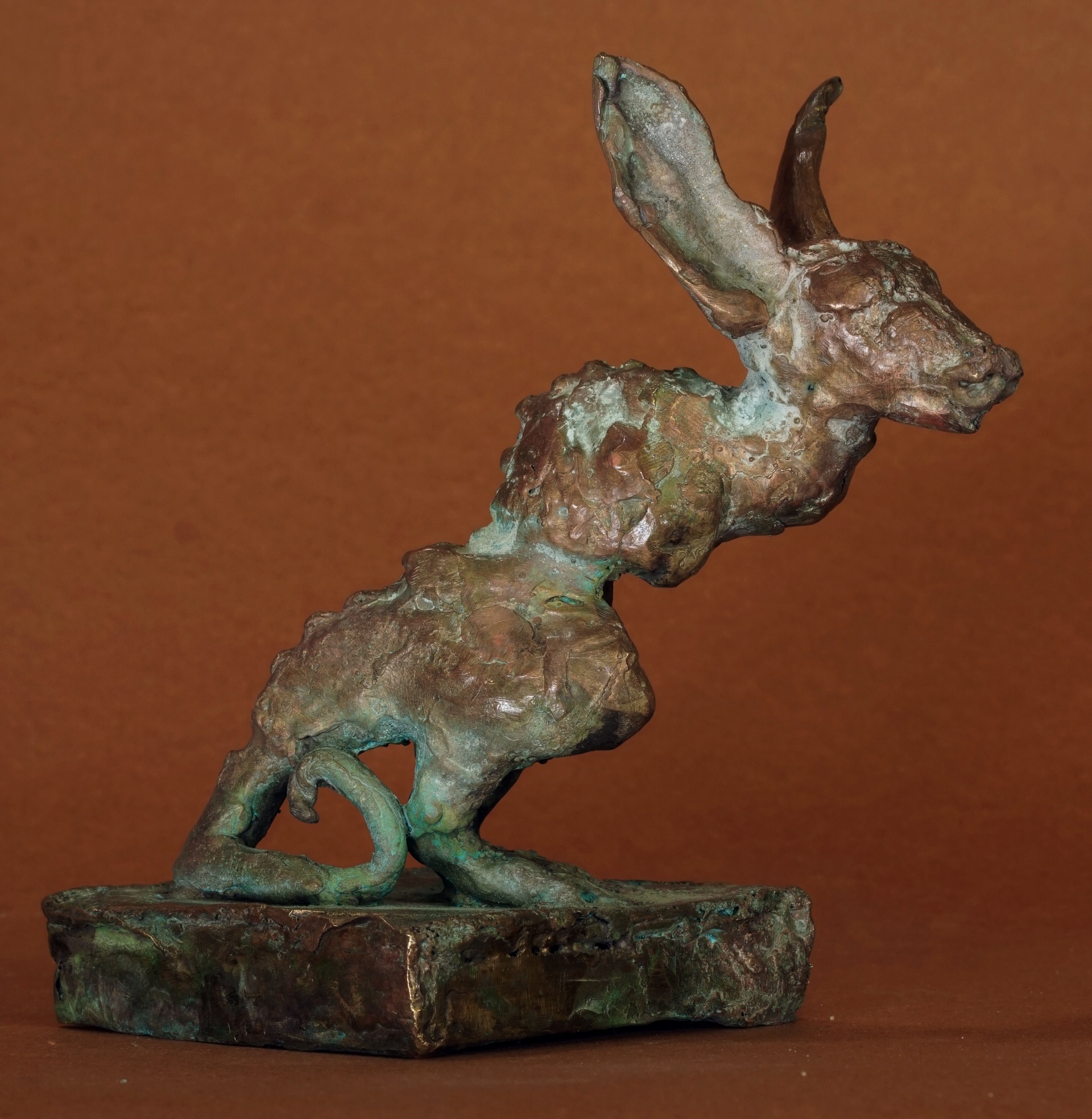 J.Osika - zdjęcie przedstawia rzeźbę fantastycznego zwierzęcia inspirowanego gryzoniami, w wielobarwnej różowo-zielono-złoto-brązowej patynie, wykonaną z mosiądzu.