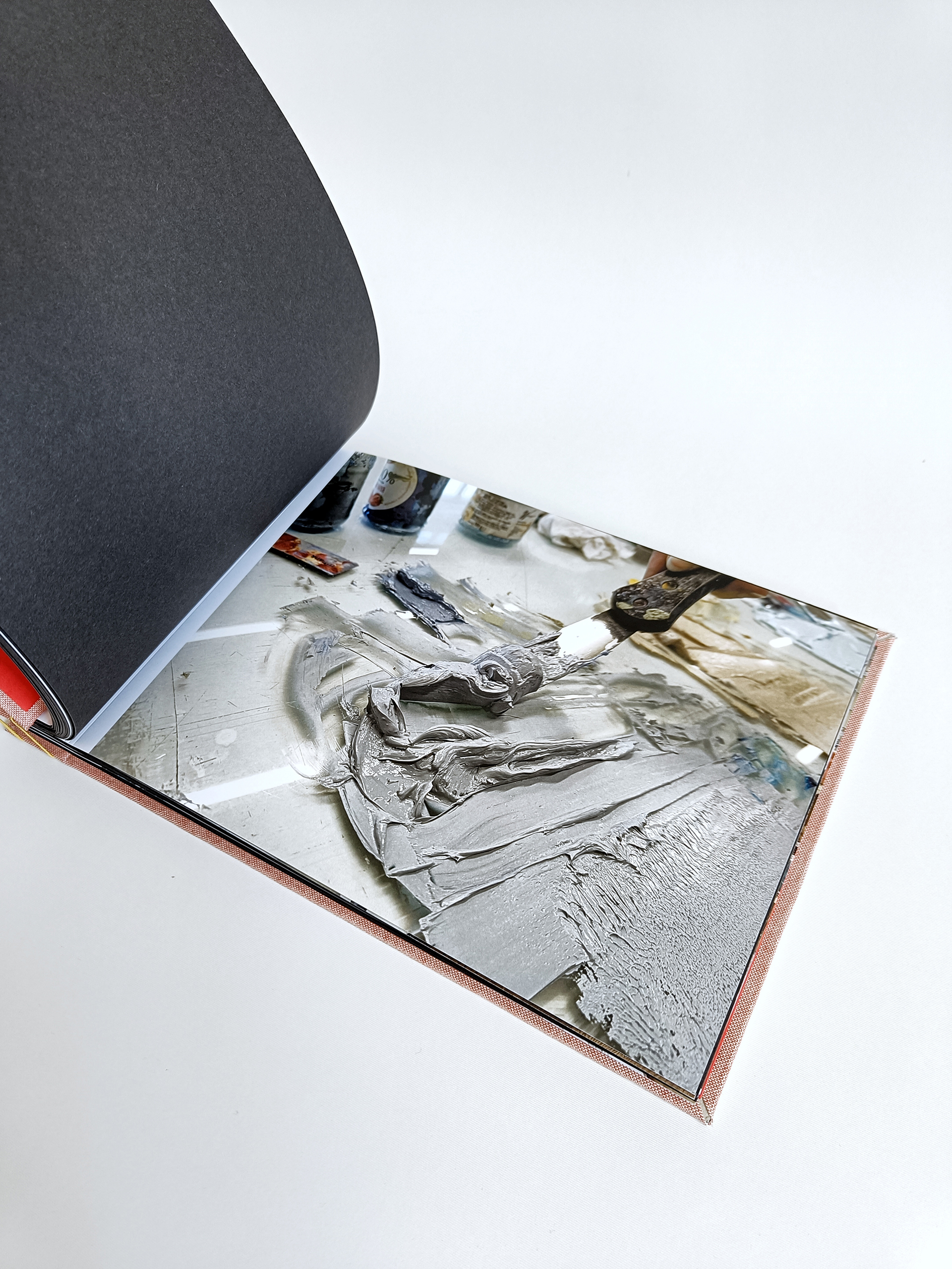 Fotografia przedstawia otwarte Portfolio w formie albumu, widoczna zdjęcie z pracowni pokazujące zbliżenie na szarą farbę drukarską.